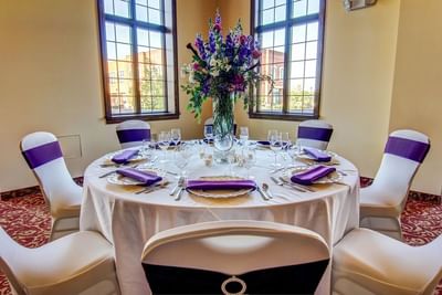 Banquet table set-up with a floral centerpiece by the window in a wedding hall at The Wildwood Hotel