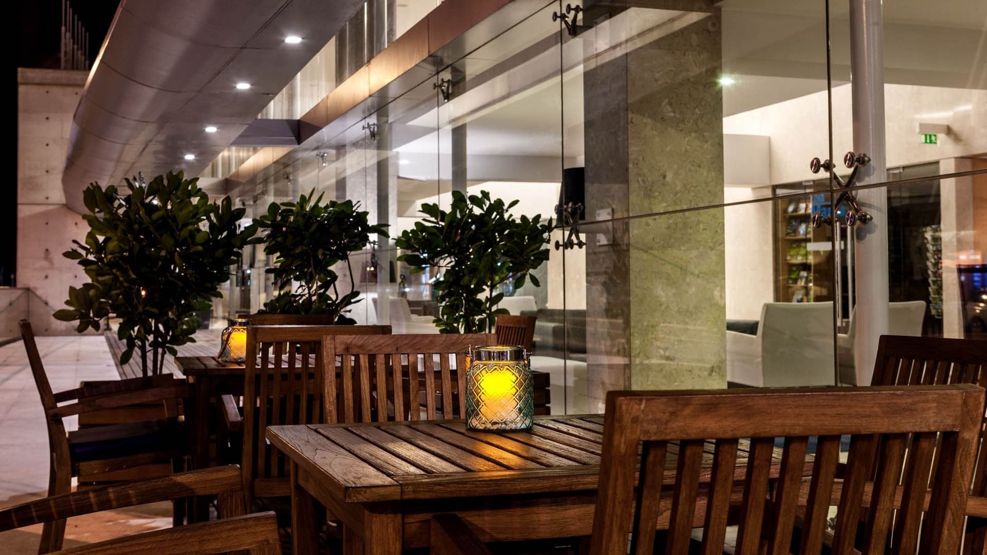 Wooden dining tables with illuminated lamps in Palhabote Bar at Hotel Marina Atlântico