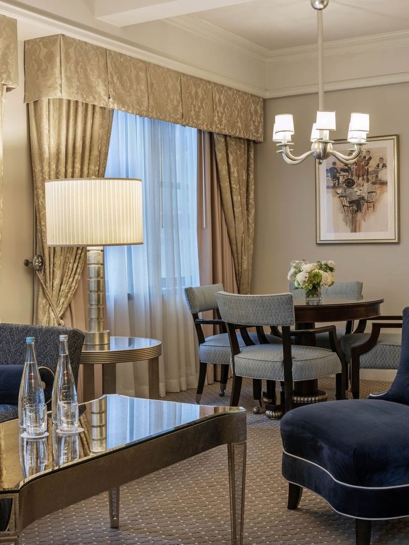 Lounge area featuring a navy velvet armchair and a sleek dining area in On the Avenue One Bedroom Suite at Warwick New York
