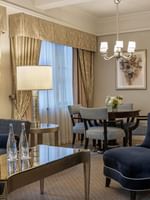 Lounge area featuring a navy velvet armchair and a sleek dining area in On the Avenue One Bedroom Suite at Warwick New York