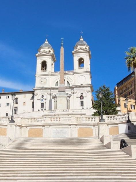 The iconic Spanish Steps lead to the Trinità dei Monti church under a bright blue sky near Rome Luxury Suites