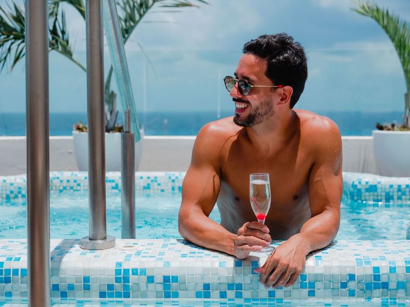 Hombre, sonriendo mientras se relaja en la piscina del Resort The Reef 28 