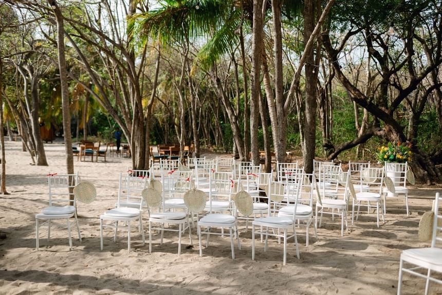 Empty white chairs with woven fans by palm trees at Morgan's Rock, a small luxury hotels Nicaragua eco retreat