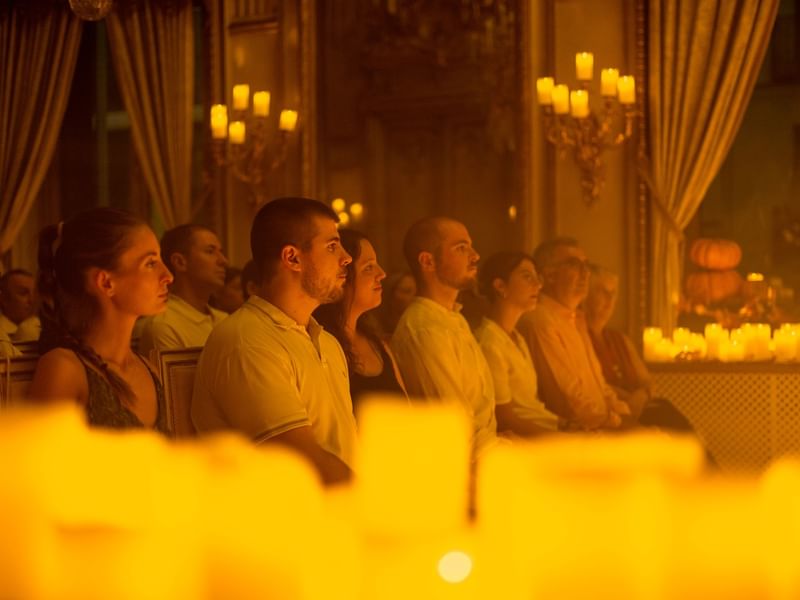 Audience seated in candlelit room watching a performance during La Fête de la Musique