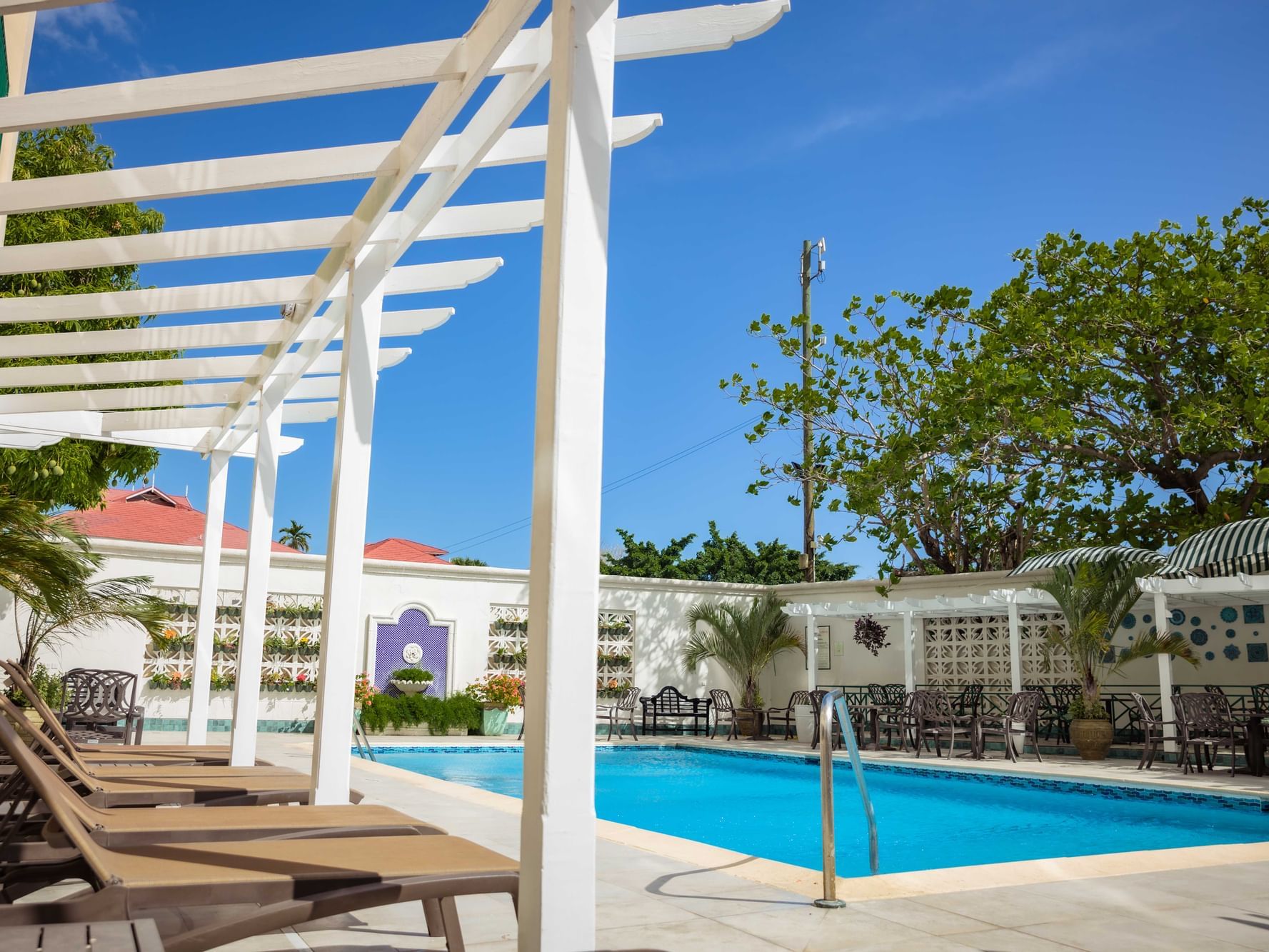 Outdoor pool with sunbeds at Courtleigh Hotel & Suites
