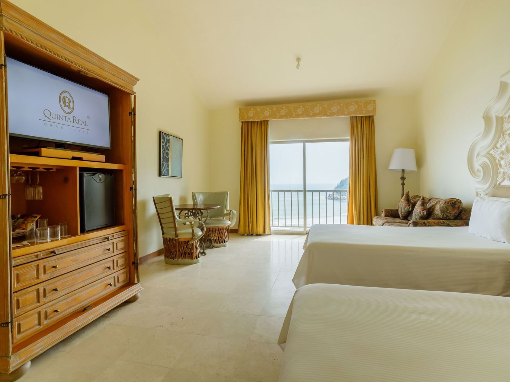 2 Double Master Suite with two beds, yellow curtains, and a balcony overlooking the sea at Quinta Real Acapulco