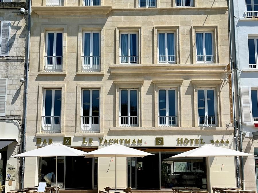 Hôtel Le Yachtman avec terrasse et entrée visibles sous un ciel bleu clair