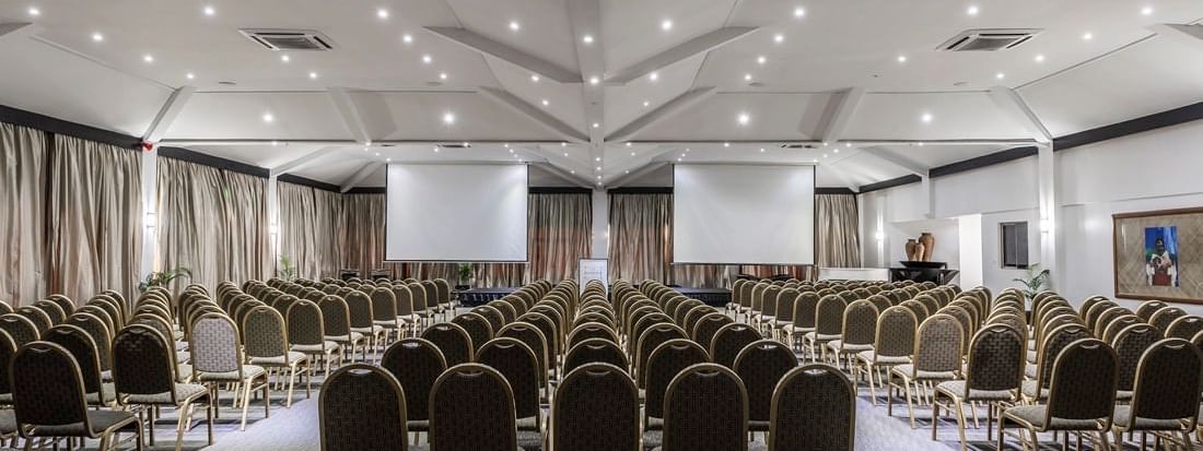 Symmetrical view of a Talanoa Hall with chairs by a center aisle under a white roof at Warwick Fiji Resort and Spa