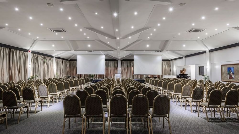 Symmetrical view of a Talanoa Hall with chairs by a center aisle under a white roof at Warwick Fiji Resort and Spa