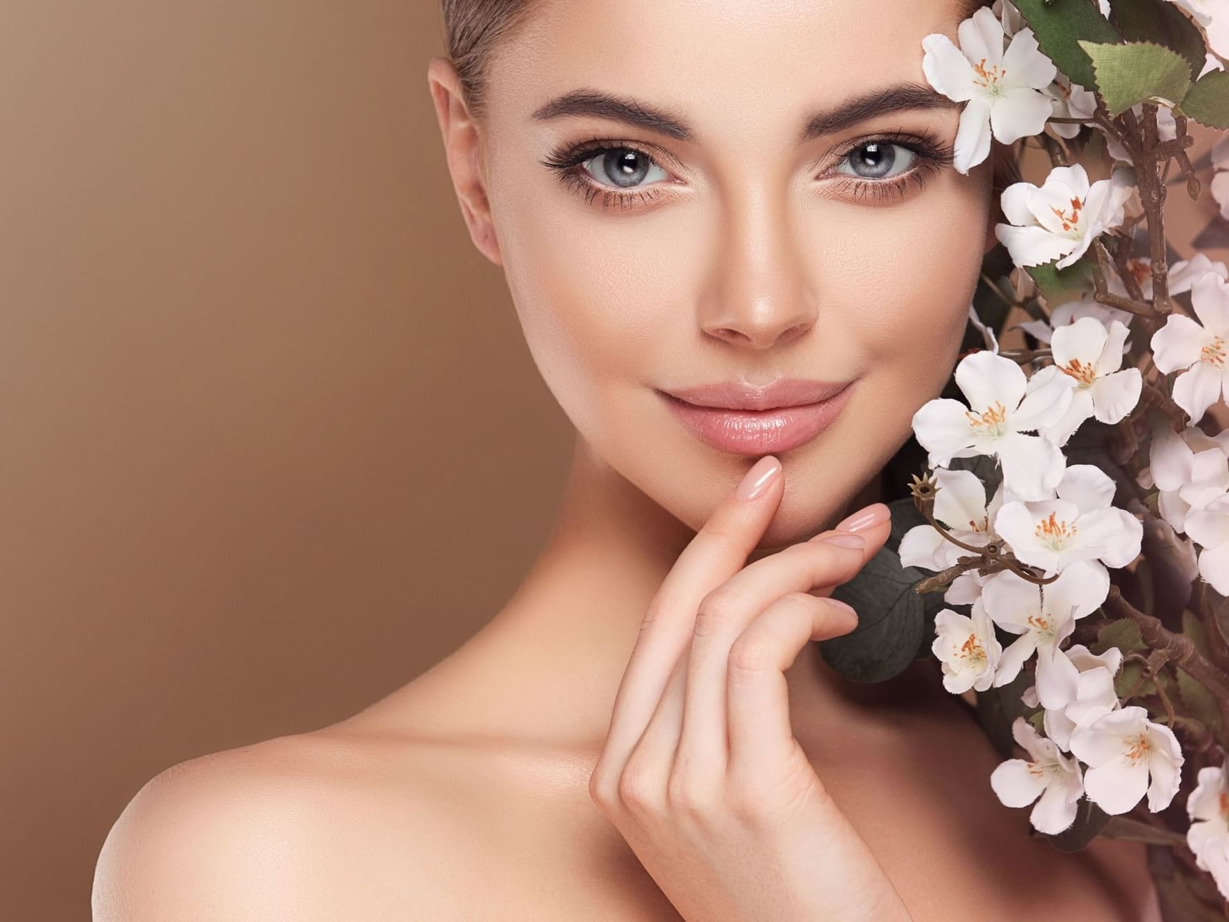 Close-up of lady gently touching her chin with one hand, surrounded by delicate white flowers at Ana Hotels Europa