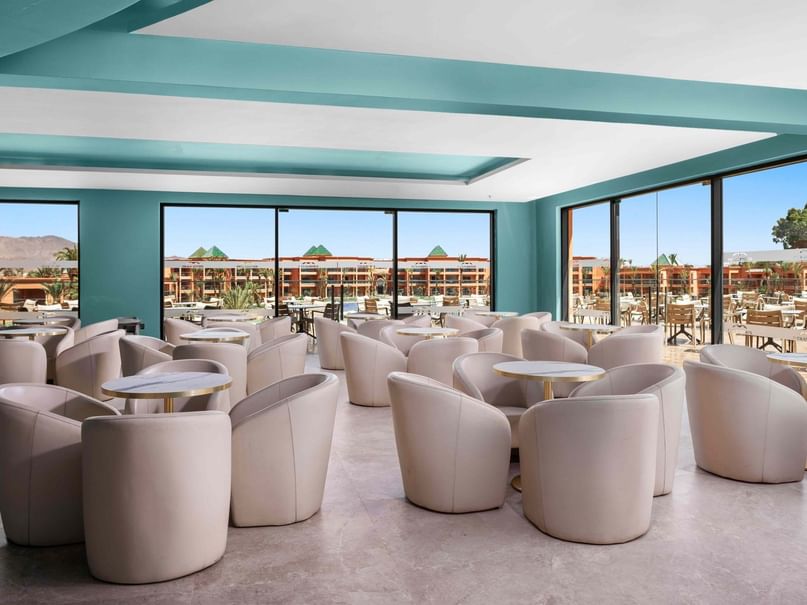 Sports Bar with large windows, beige chairs, and round tables with a view of the resort.