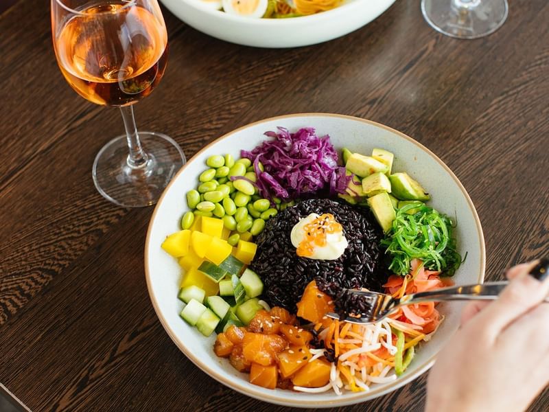 Close-up of various veggies and black rice & glass of wine in the restaurant at Crown Hotels