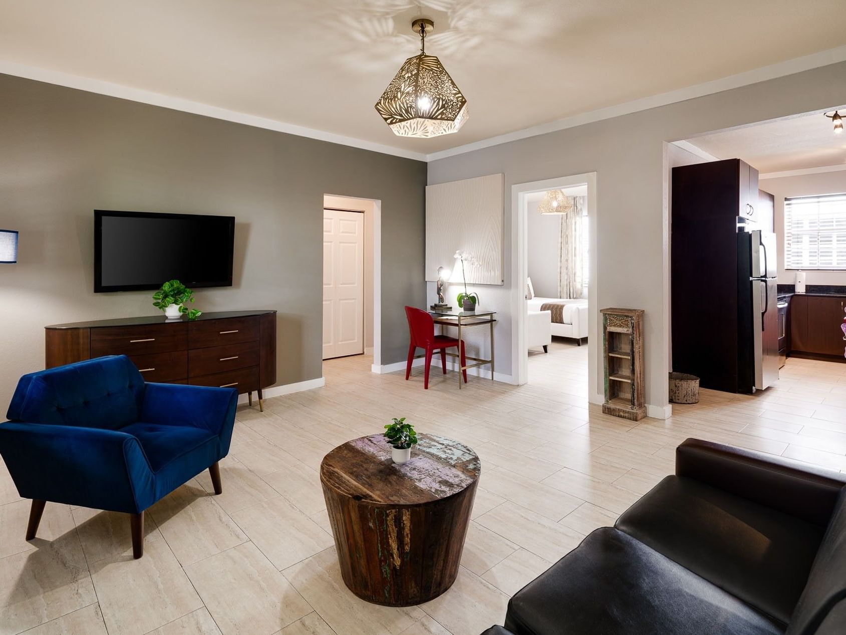 One Bedroom Double Queen Suite with a blue velvet armchair and light tile floors at Tradewinds Apartment Hotel