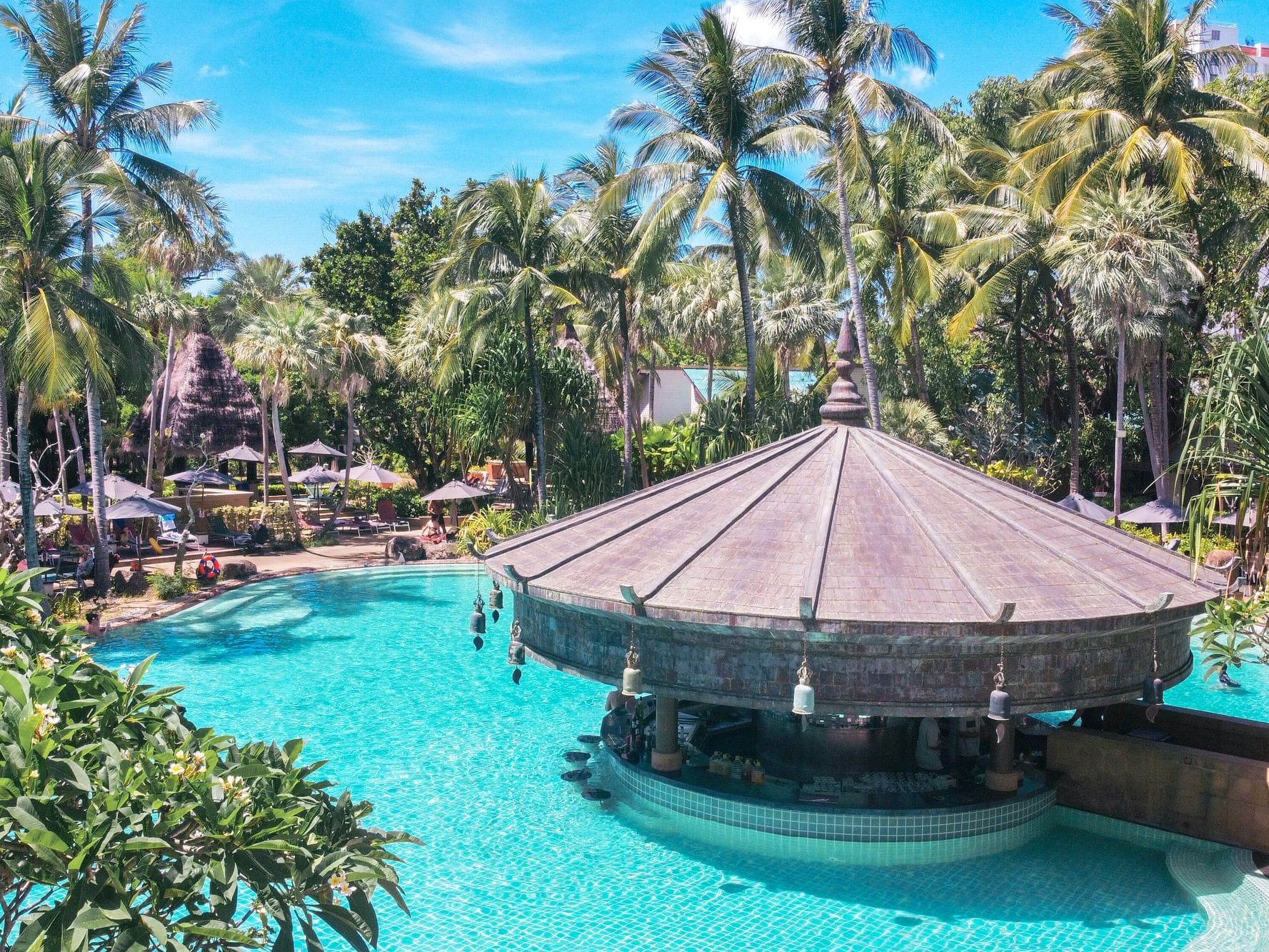 Main Pool and Pool bar are surrounded by the tropical and coconut trees on the sunny day