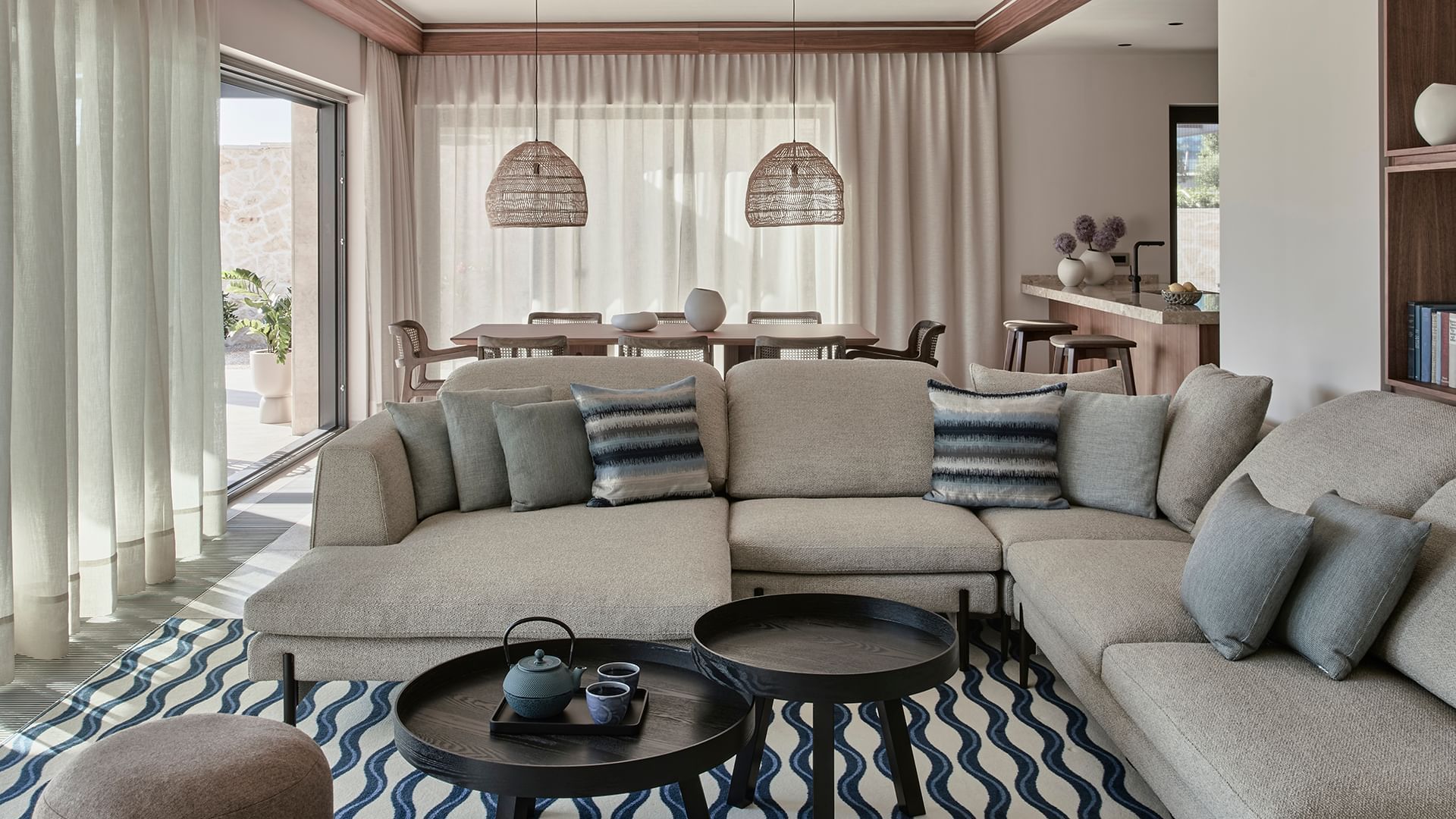 Living room with sectional sofa, rug, and wicker pendant lights in Villa Anastasia at Falkensteiner Resort Punta Skala