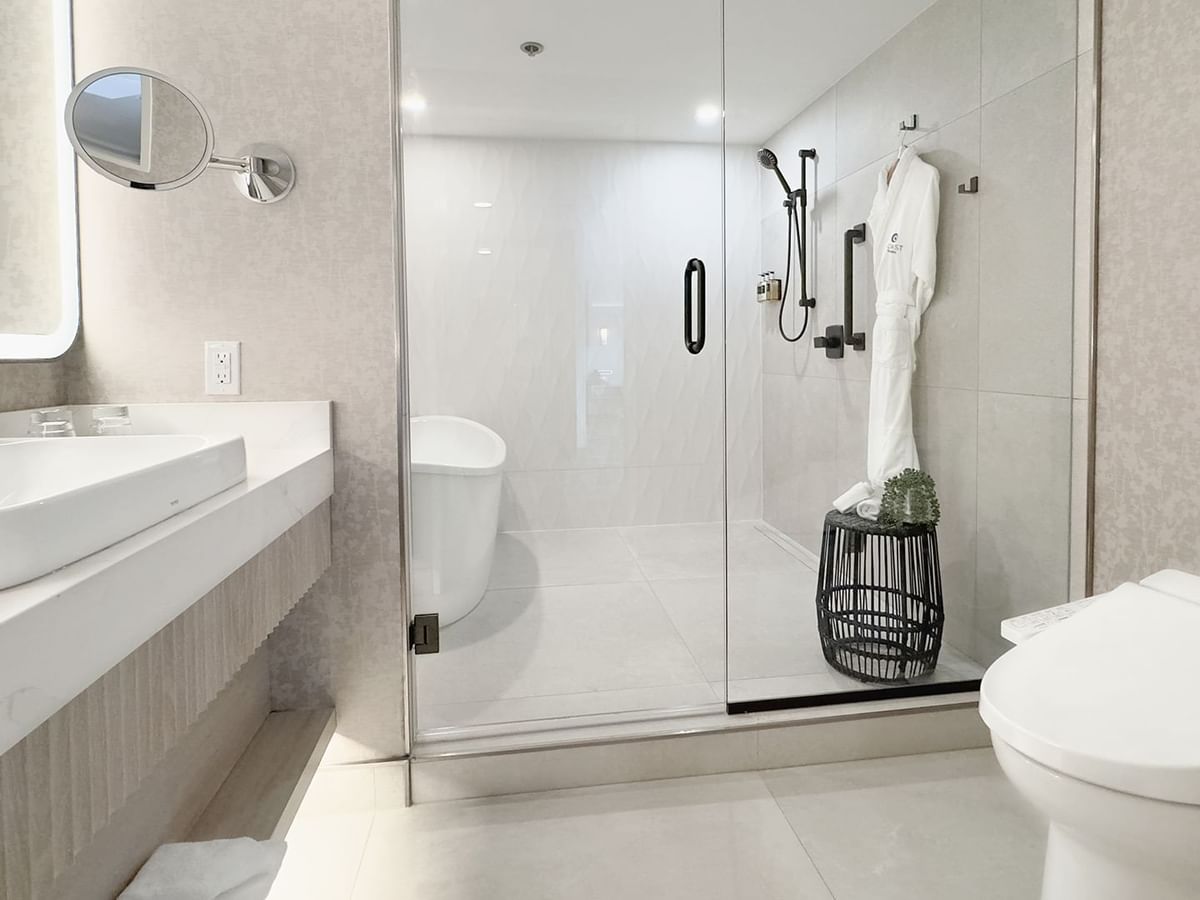 Hotel washroom with toilet, sink, bath tub, shower,  soap, and towels