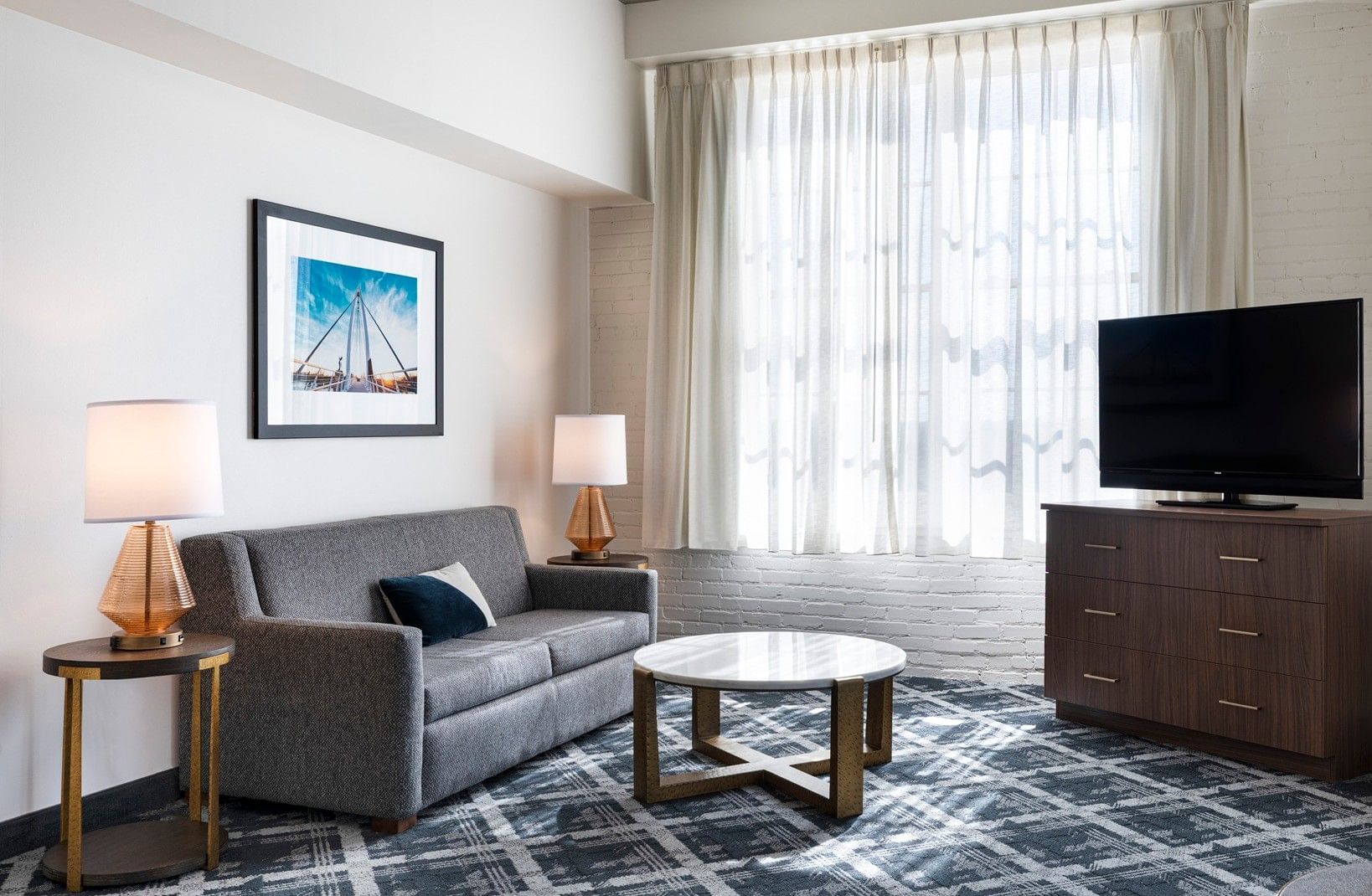 A living room with a gray sofa, coffee table, TV, and lamps.