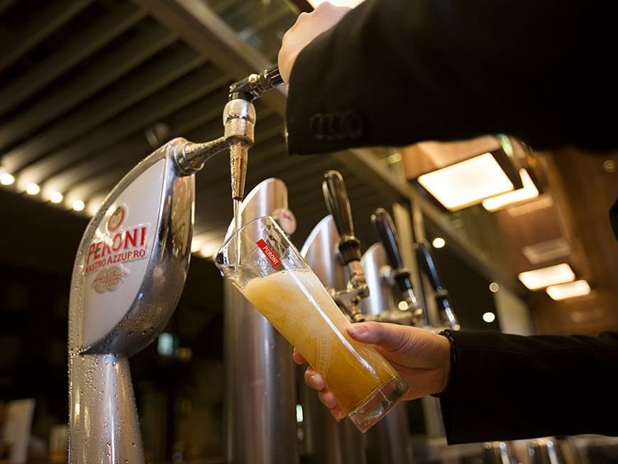 Hands pouring beer into glass at Amara Hotel Singapore