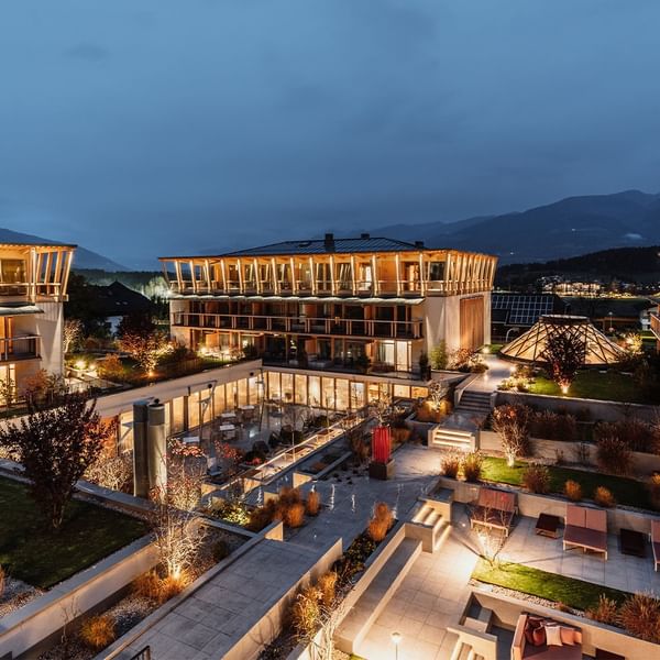 Evening view of a modern hotel complex with illuminated buildings and terraces at Falkensteiner Group