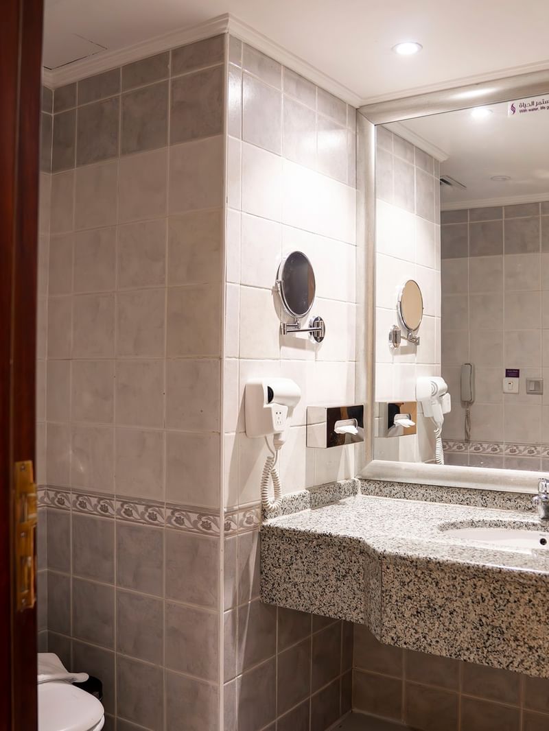 حمام عصري مزود بمغسلة ومرآة ومرحاض في غرفة خماسية قياسية في فندق سجى ورويك المدينة المنورة.