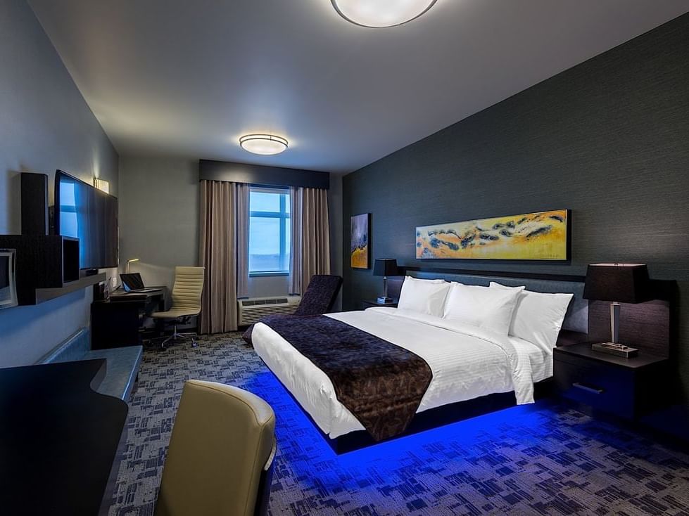 Comfy beds with a TV & work desk in Deluxe King Room at Applause Hotel Calgary