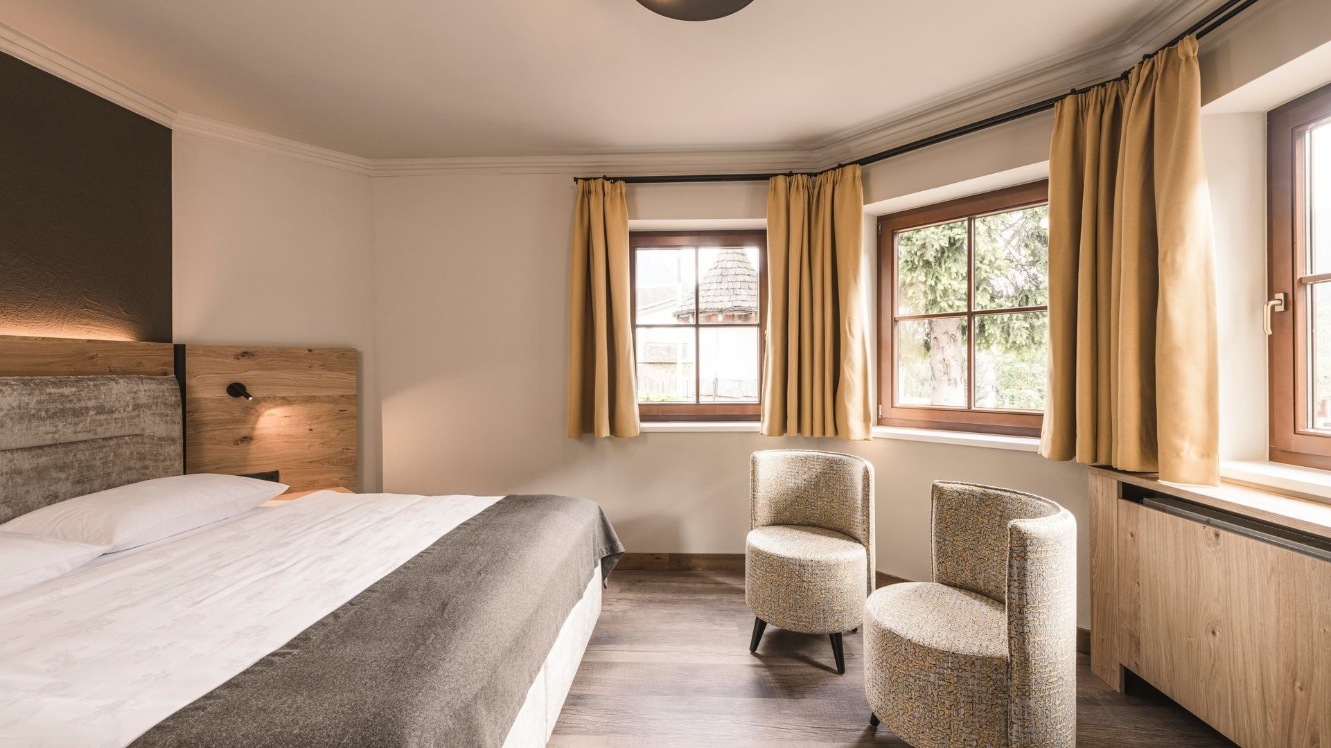 Junior Garden Suite con letto, sedie e finestre al Falkensteiner Hotel Falkensteinerhof, Valles.