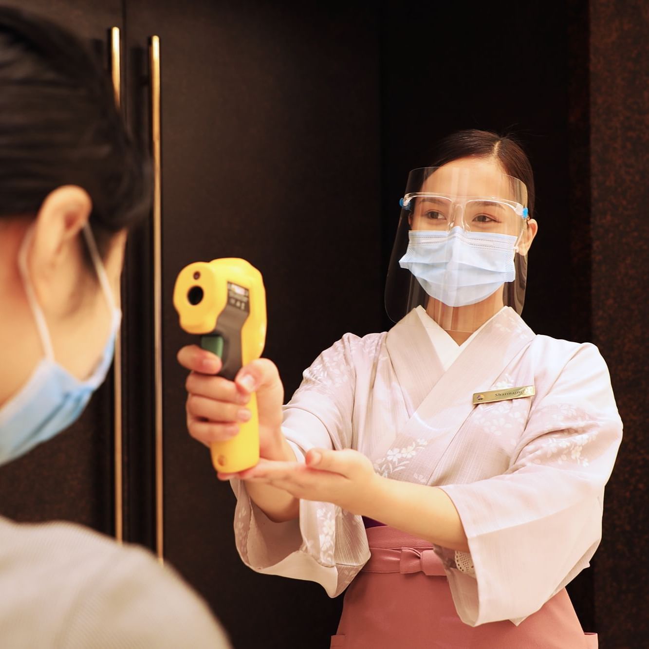 Receptionist checking temperature at Hotel Okura Manila