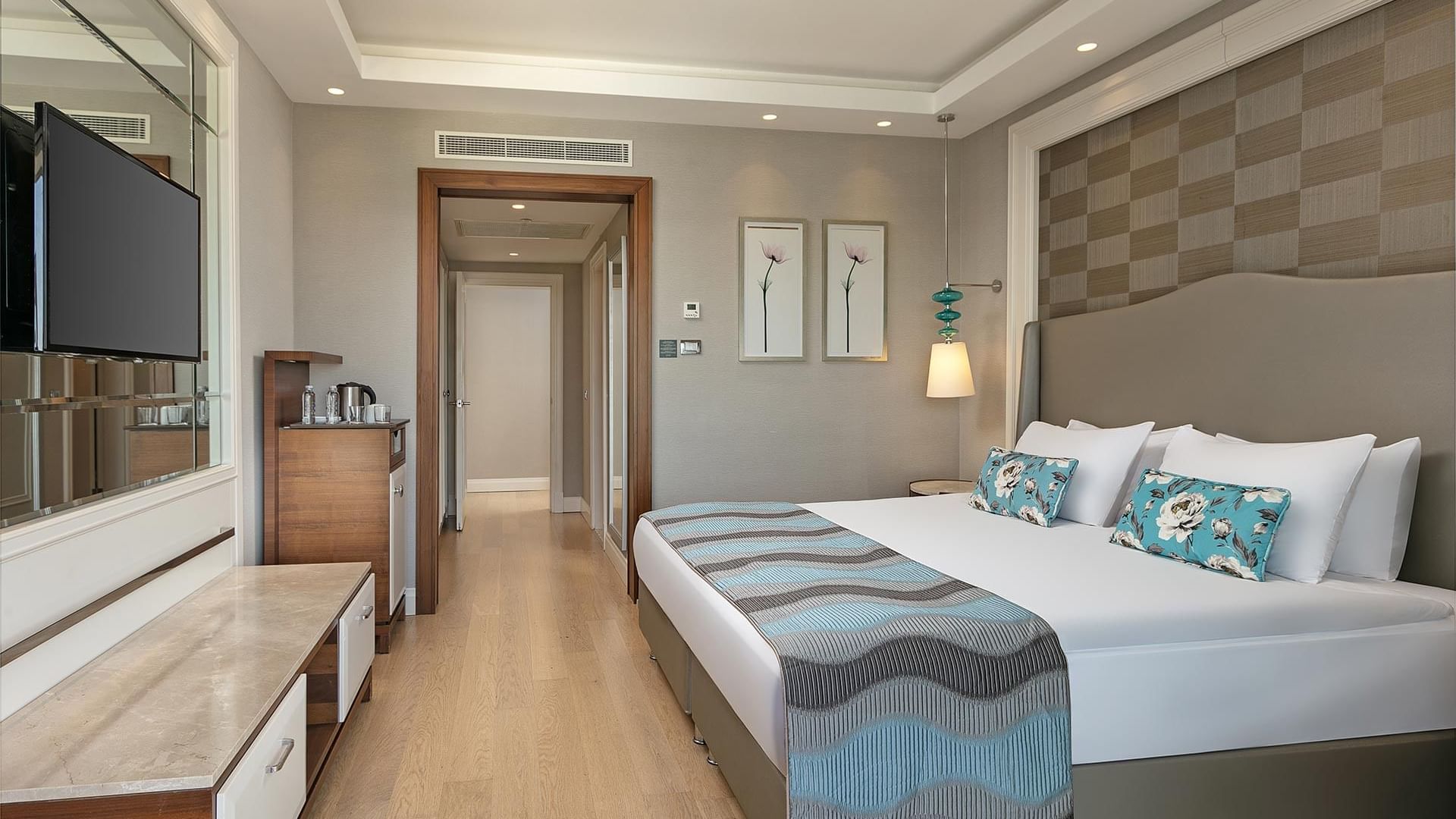 Titanic Deluxe Golf Belek’te Major Süit’te, ahşap zeminli odada yatak yanında TV ve kahve makinesi.