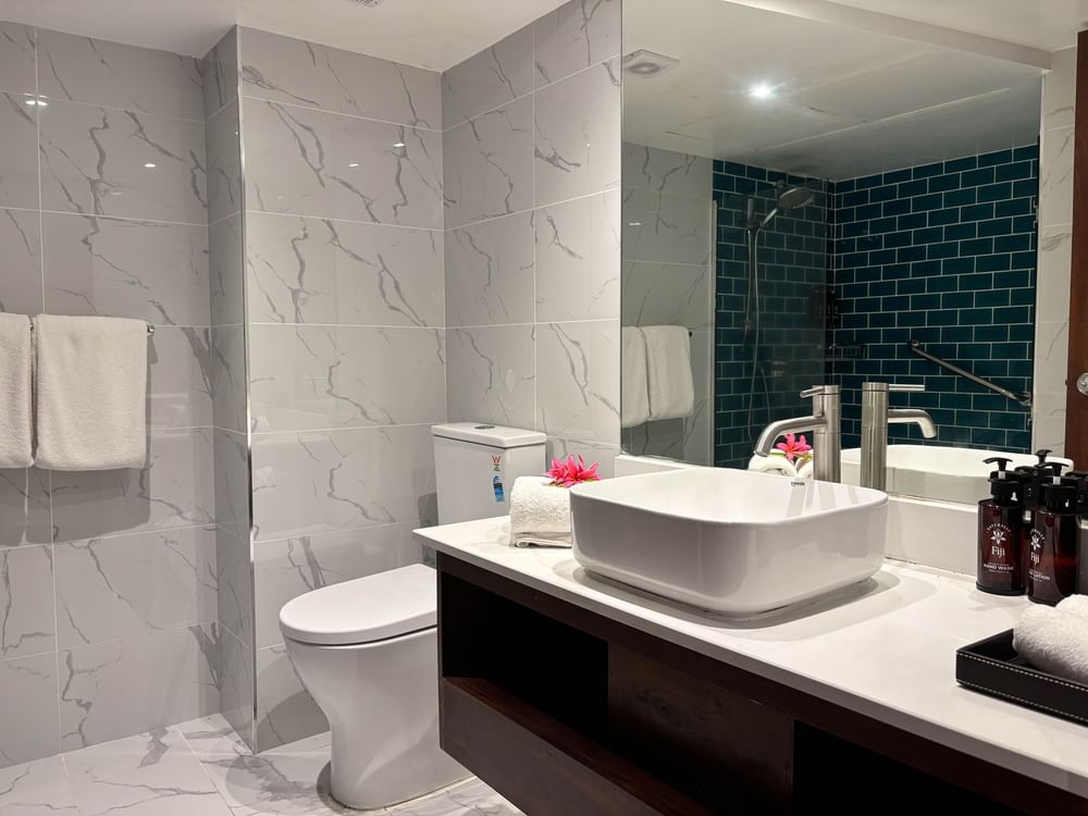 Modern bathroom with large sink, toilet, and mirror at Warwick Fiji Resort and Spa in Korolevu.