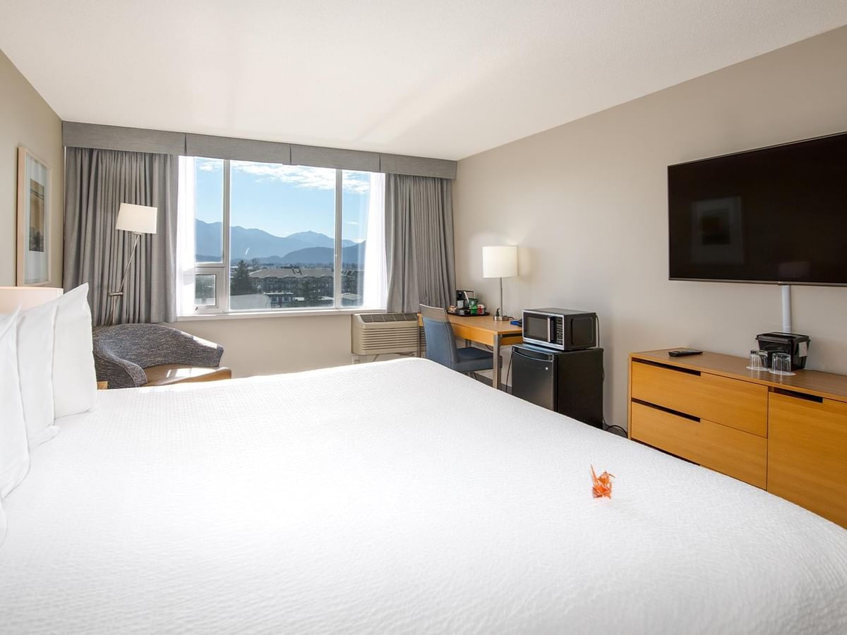 Spacious room with a large bed, desk, and pond view.