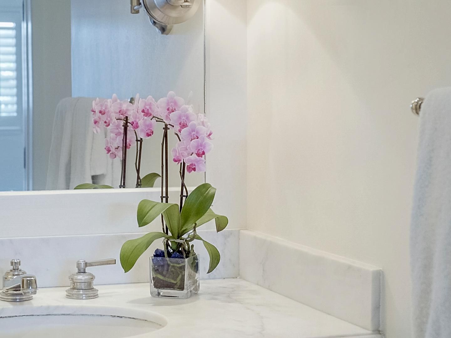 Bathroom vanity with a floral vase in Deluxe ADA Room 305 at Pavilion Hotel