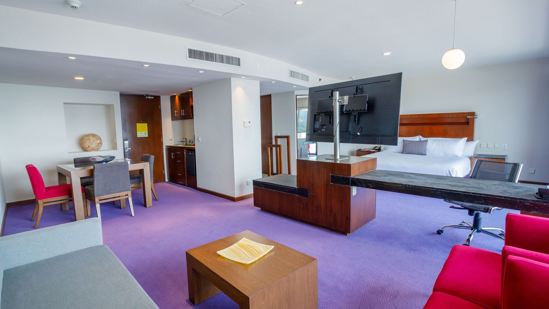 King Master Suite at Camino Real Pedregal Mexico, with a dining area, purple floors, and a swiveling TV unit