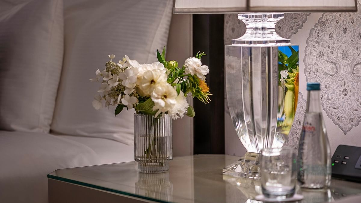 Elegant bedside table with flowers, lamp, and water bottle in an Accessible Premier City View room at Warwick New York