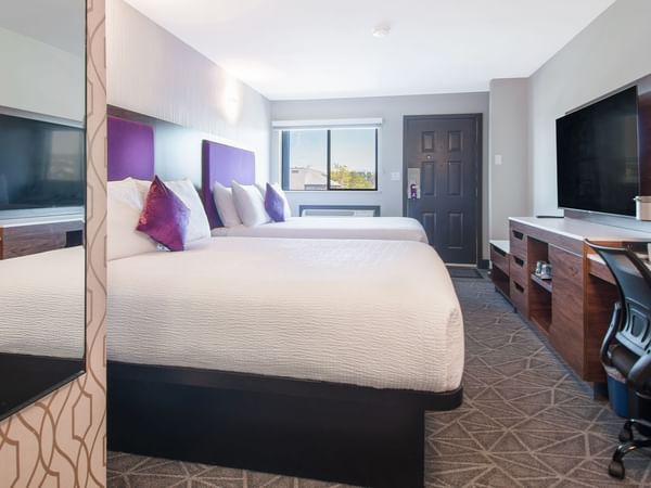 Hotel guestroom with two queen beds, flat screen TV, work desk and chair