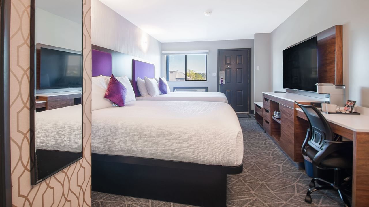 Hotel guestroom with two queen beds, flat screen TV, work desk and chair
