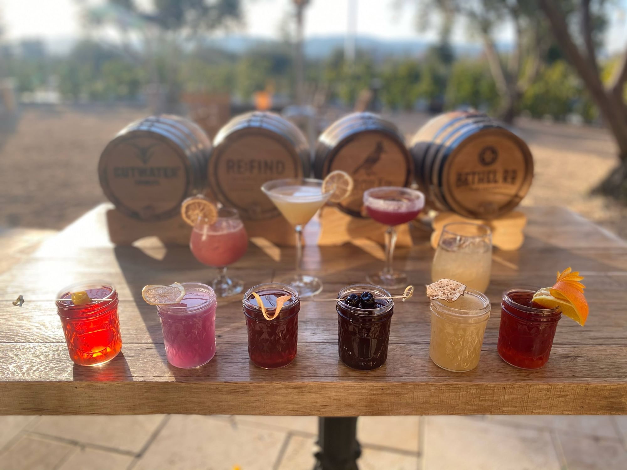 A line of handcrafted cocktails in front of barrels