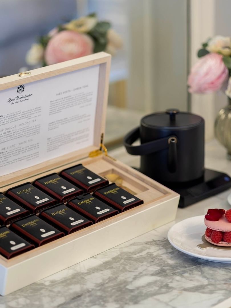 Box of Dammann teas, a macaron, and a tea set on a marble table at Hôtel Westminster Paris.