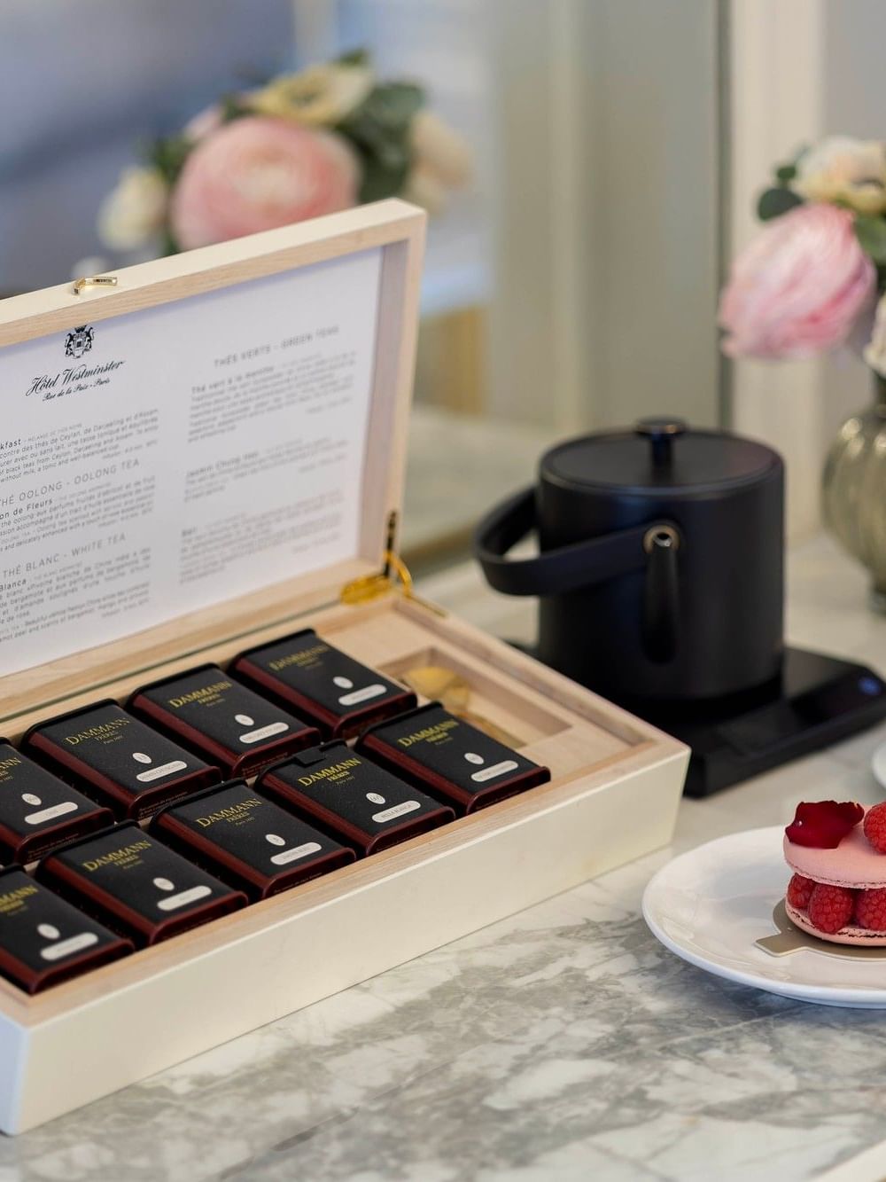 Box of Dammann teas, a macaron, and a tea set on a marble table at Hôtel Westminster Paris.