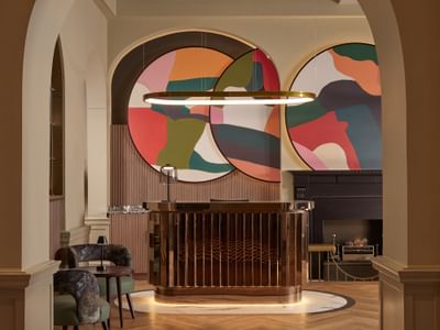 Chic lobby of The Met Hotel Leeds, England, with a modern copper reception desk, abstract art, and a fireplace