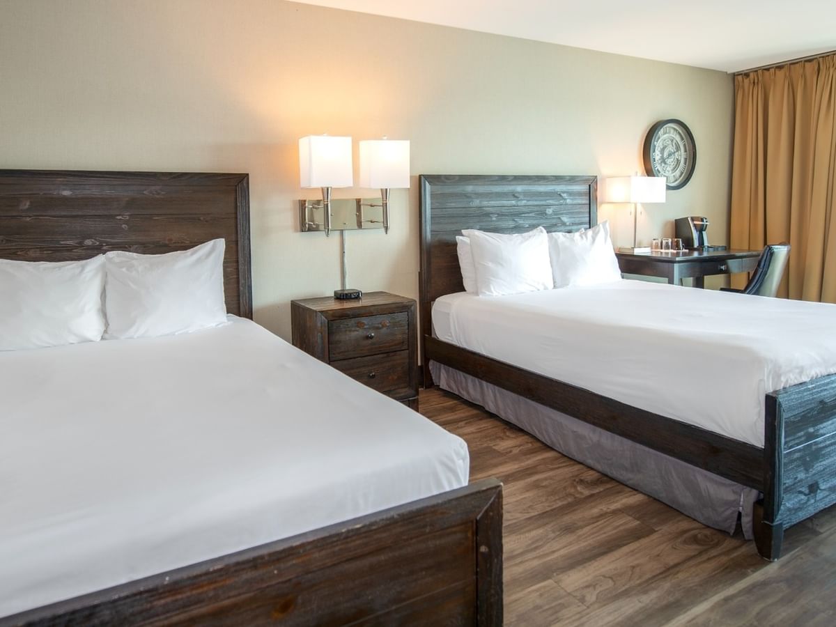 Coast Two Queens room with two queen beds, nightstands with lamps, and a desk near a glass door at Coast Lonsdale Quay Hotel