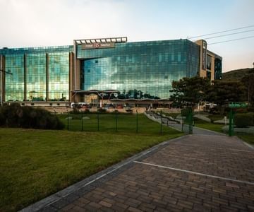 Exterior of Hotel B3 Sibelius with a glass facade by a paved walkway and green lawn, a featured hotel in Bogota, Colombia