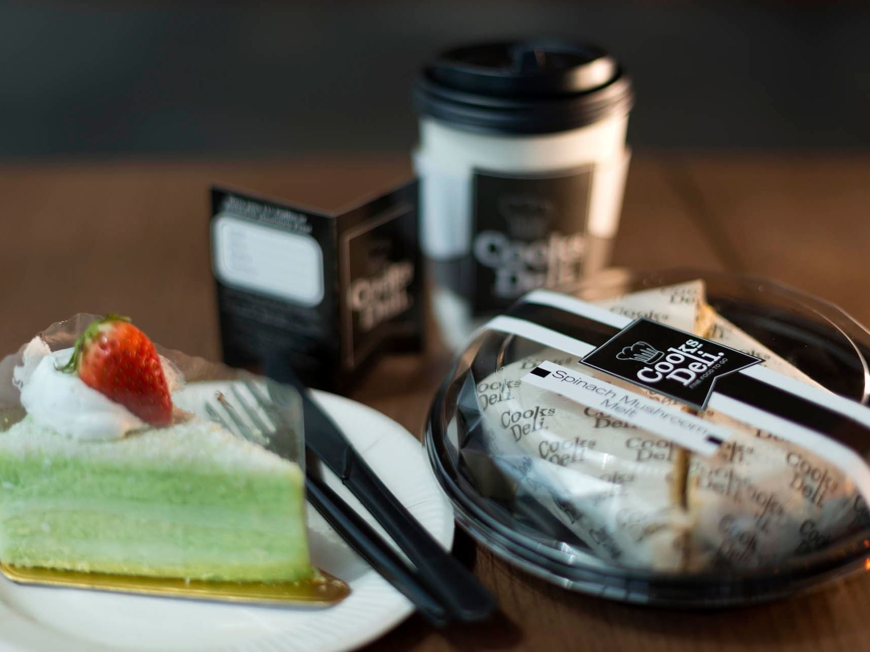 Close-up of cake slice, coffee cup and container with a wrap served in Cooks Deli at Saujana Hotel Kuala Lumpur