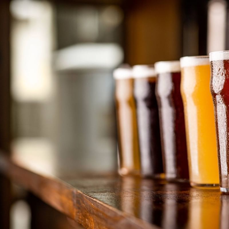 Close-up of a variety of beers served in glasses on a wooden bar counter at Warwick Hotels and Resorts