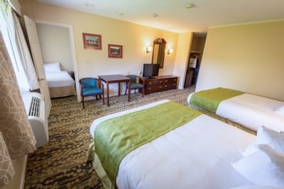 Fox Ridge Resort room with two queen beds, and two twin beds with a table, chairs, a dresser, and a mirror.