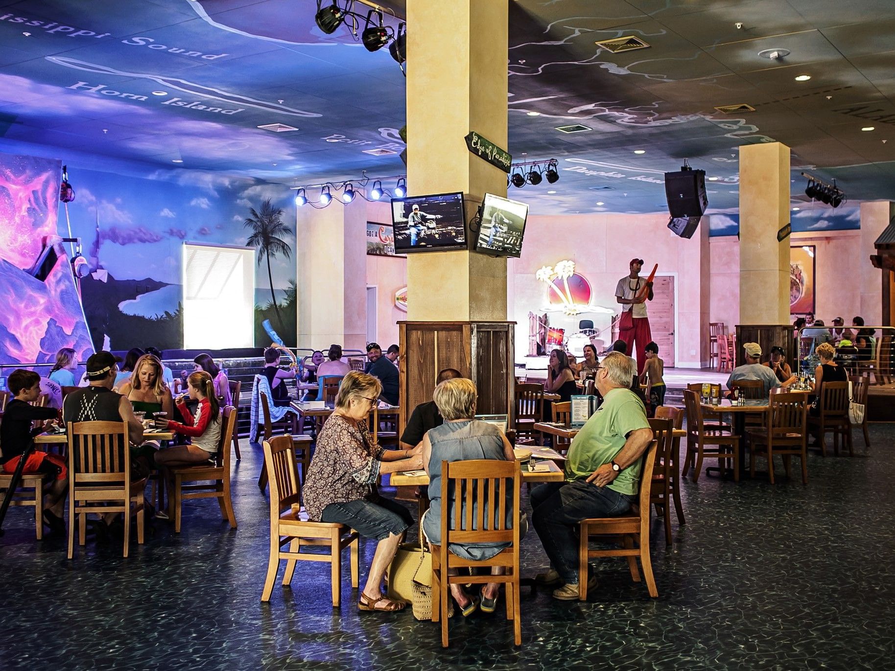 Vibrant dining area in Margaritaville Café at Margaritaville Resort Biloxi with guests eating under a coastal themed ceiling
