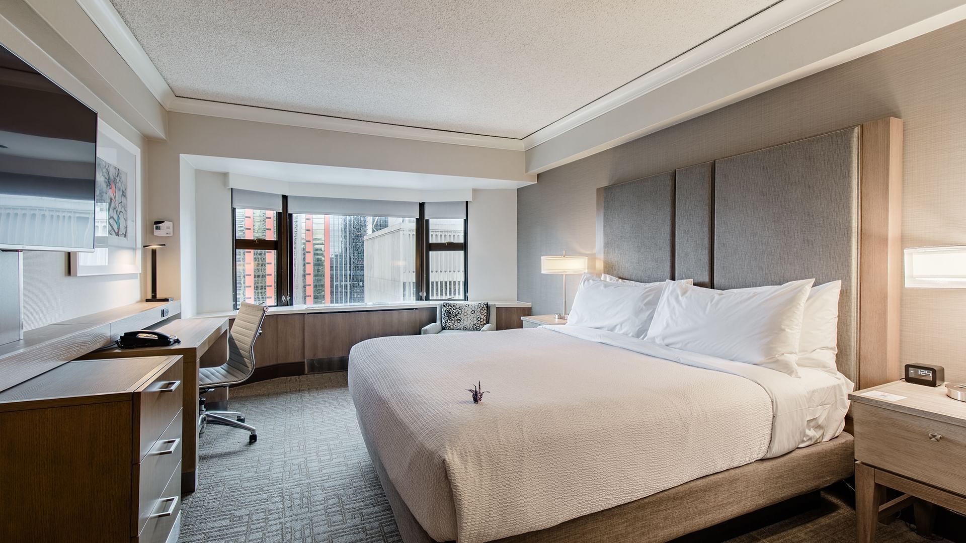 A wide view of a hotel room with a large bed, desk, and window.