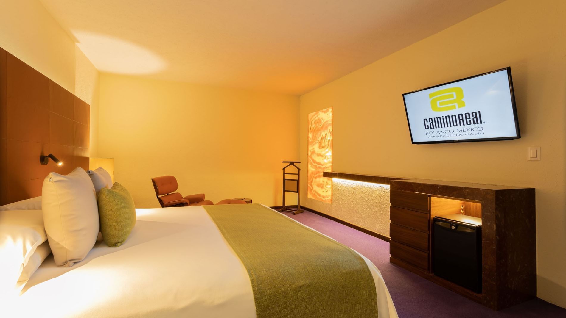 Suite Junior King con TV en pared mostrando el logo del hotel y cama en Camino Real Polanco México