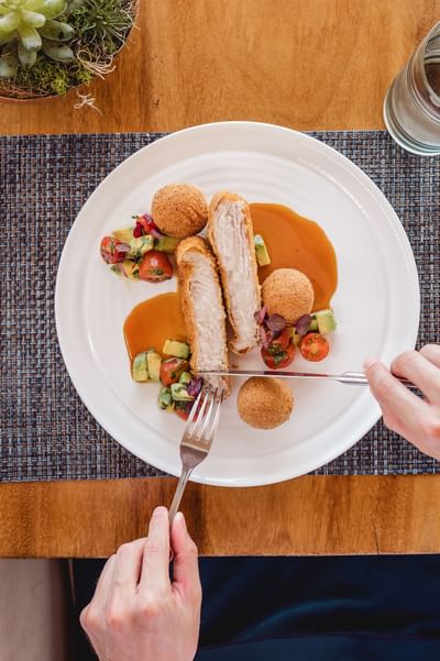 A person having chicken drumsticks and mini kieve balls dish in La Playa Restaurant at Amaka Ocean Living Lodge