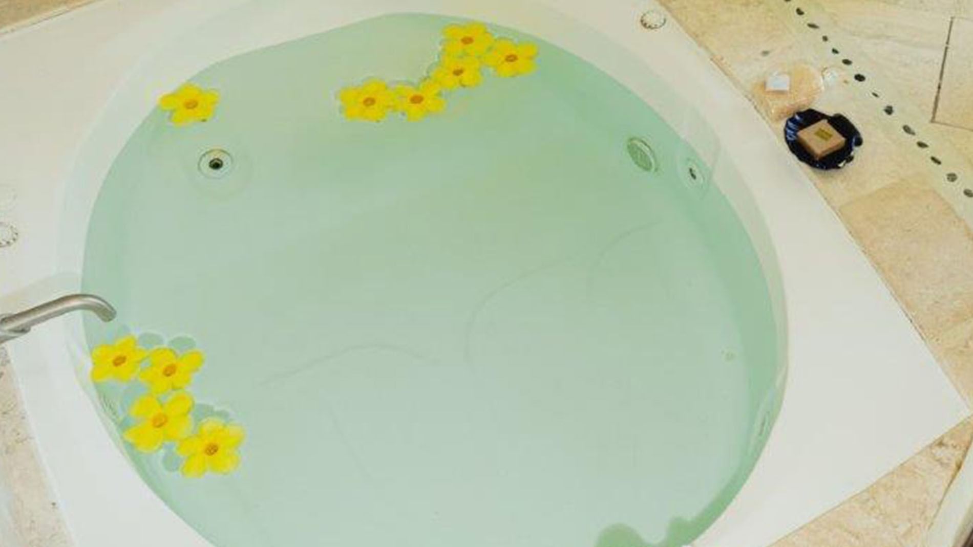 King Master Suite Close-up of a relaxing soaking tub decorated with bright yellow floating flowers at Quinta Real Huatulco