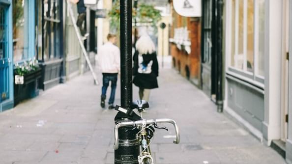 Bicycle parked by a signpost on a street near Originals Hotels